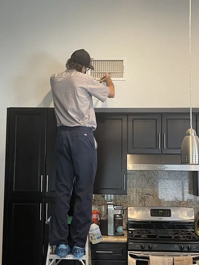 Technician inspecting an air vent during HVAC service in West Chicago